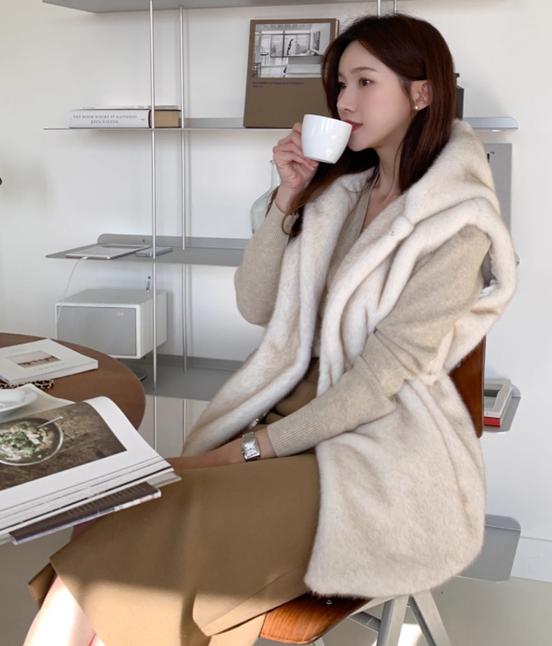 フェイクミンクファーベストを着用して椅子に腰かけたイメージ